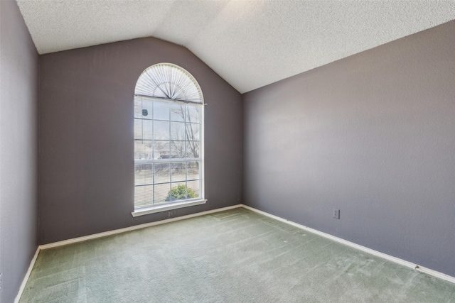 empty room with lofted ceiling, carpet floors, a textured ceiling, and baseboards