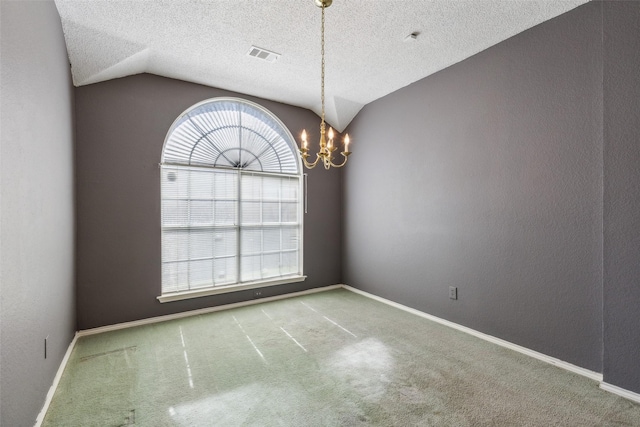 empty room featuring lofted ceiling, a notable chandelier, visible vents, and carpet flooring