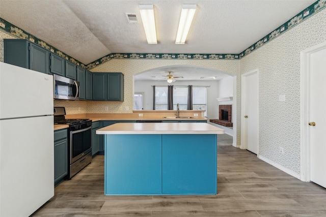 kitchen with wallpapered walls, stainless steel appliances, and a sink