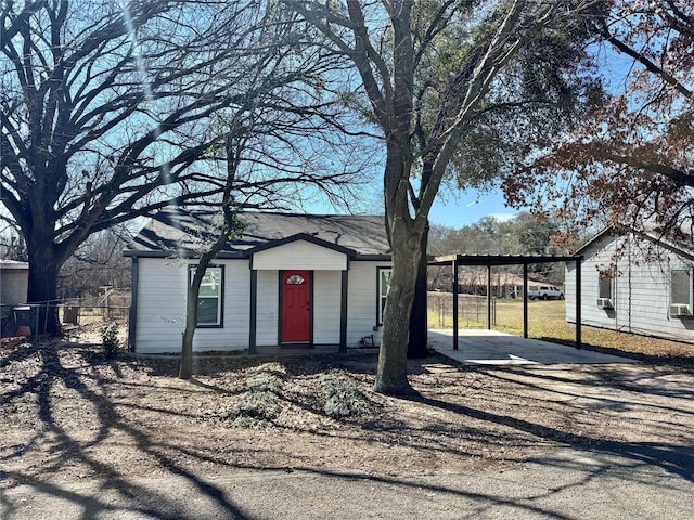 exterior space featuring dirt driveway, a carport, and fence