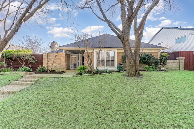 view of front of home featuring brick siding, fence, roof with shingles, a chimney, and a front yard