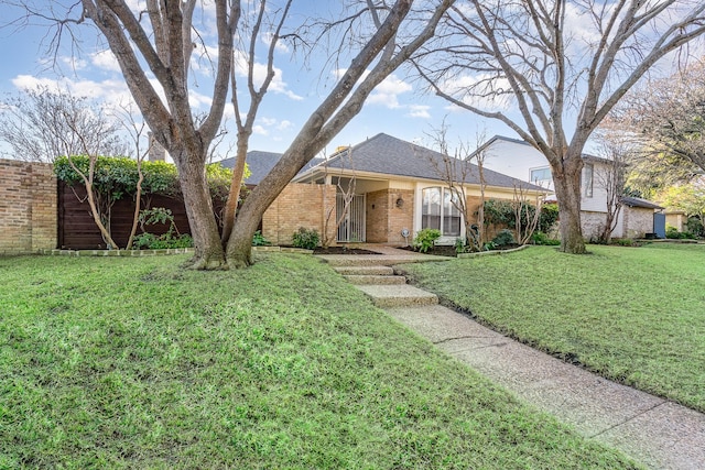 ranch-style house with roof with shingles, a front lawn, and brick siding