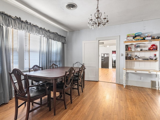 dining space featuring a chandelier, light wood-style flooring, and visible vents