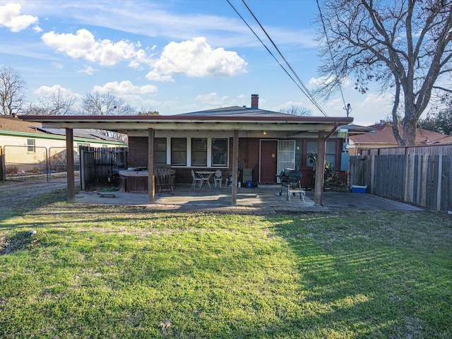 back of property featuring a lawn, a fenced backyard, a chimney, a patio area, and brick siding