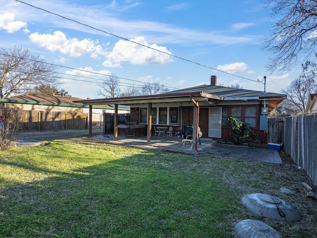 back of house with a patio, a lawn, a chimney, and a fenced backyard