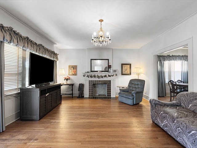 living area with baseboards, light wood finished floors, a tile fireplace, and a notable chandelier