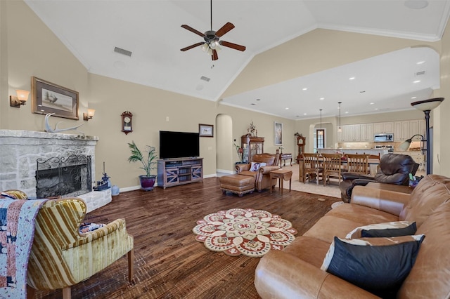 418 Navajo Trl, Gainesville, TX 76240 - living area with arched walkways, a stone fireplace, wood finished floors, visible vents, and crown molding