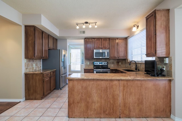 kitchen with light tile patterned floors, visible vents, appliances with stainless steel finishes, a sink, and a peninsula