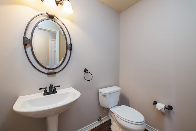 half bathroom featuring a sink, toilet, and baseboards