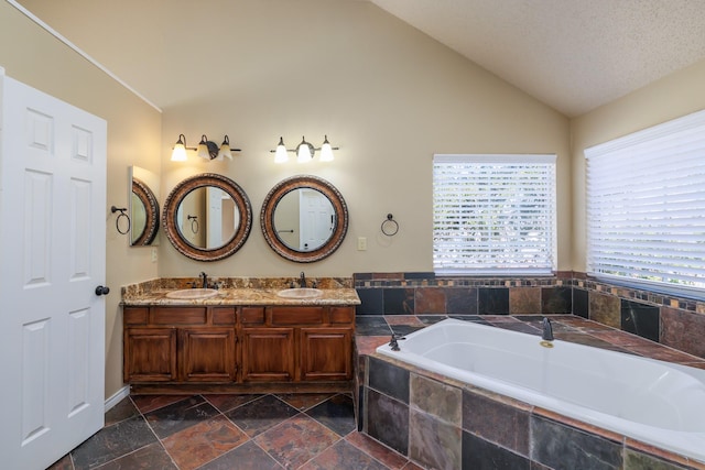 full bathroom with lofted ceiling, a sink, stone tile flooring, and a bath