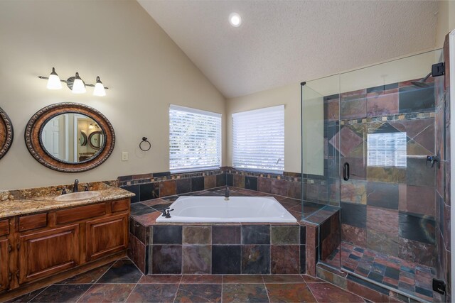 bathroom with stone tile floors, lofted ceiling, a stall shower, vanity, and a bath