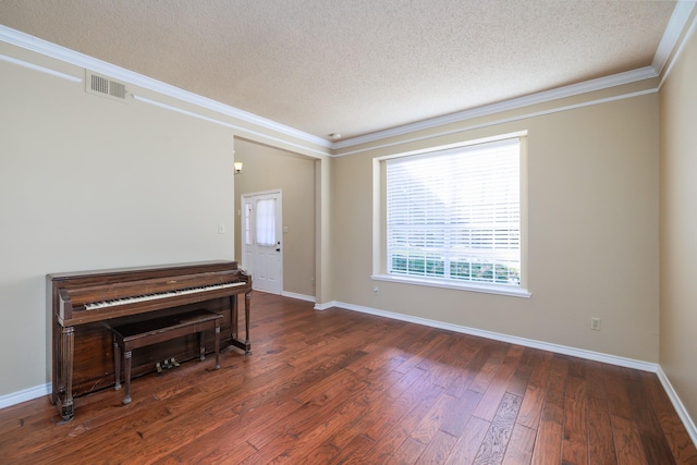 interior space featuring visible vents, hardwood / wood-style floors, ornamental molding, a textured ceiling, and baseboards