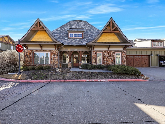 view of front facade with an attached garage, stone siding, and driveway