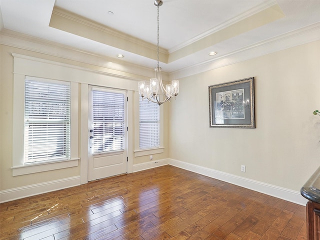 unfurnished dining area with a tray ceiling, wood-type flooring, and baseboards