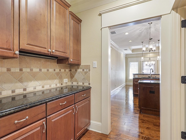 kitchen with dark wood-style floors, decorative backsplash, brown cabinets, and crown molding