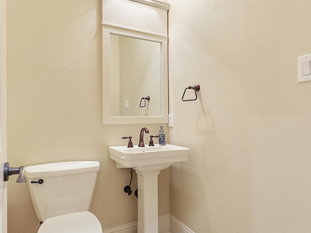 bathroom featuring baseboards, a sink, and toilet