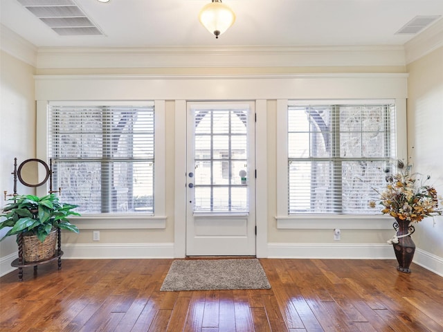 doorway to outside featuring ornamental molding, wood-type flooring, visible vents, and baseboards