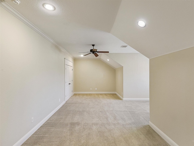 additional living space with light carpet, visible vents, baseboards, lofted ceiling, and ceiling fan