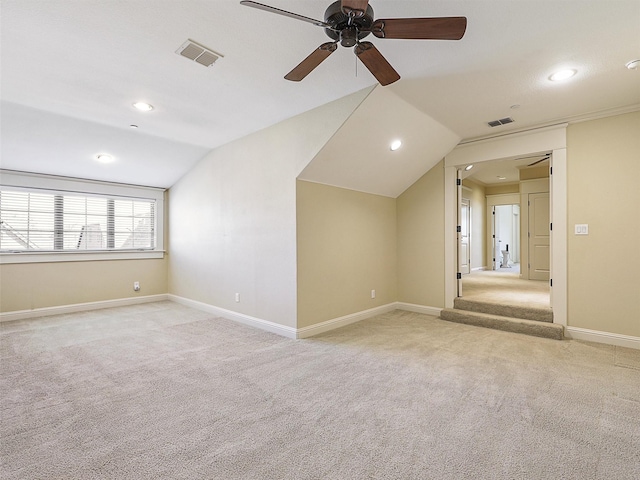 empty room featuring light colored carpet, visible vents, lofted ceiling, and baseboards