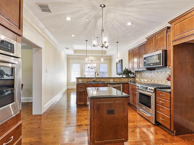 kitchen with a notable chandelier, stainless steel appliances, a sink, visible vents, and dark countertops