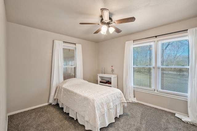 bedroom with a ceiling fan, dark colored carpet, and baseboards