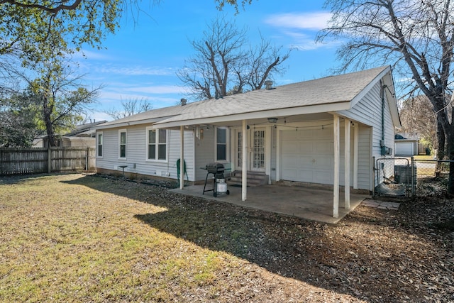 exterior space with an attached garage, fence, a front yard, driveway, and a patio area