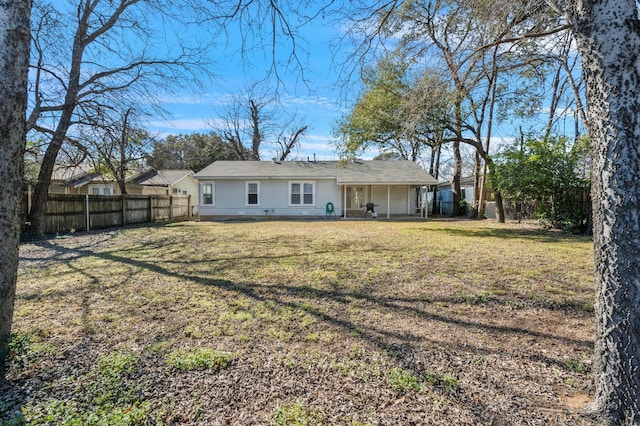 rear view of house featuring a lawn and a fenced backyard