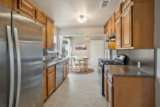 kitchen featuring stainless steel appliances, brown cabinetry, and under cabinet range hood