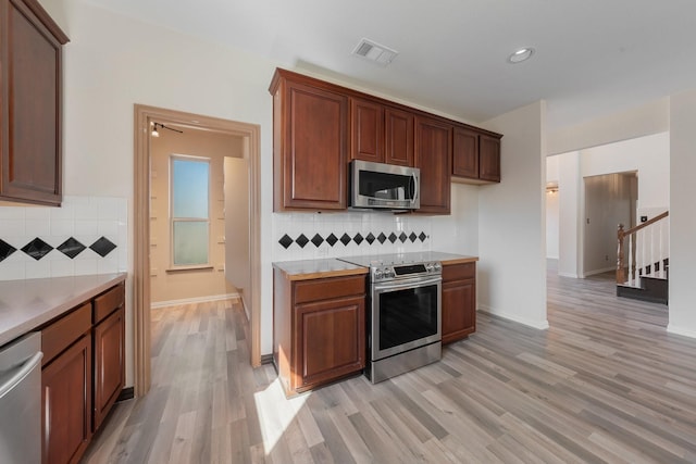 kitchen featuring stainless steel appliances, tasteful backsplash, light countertops, visible vents, and light wood-style floors