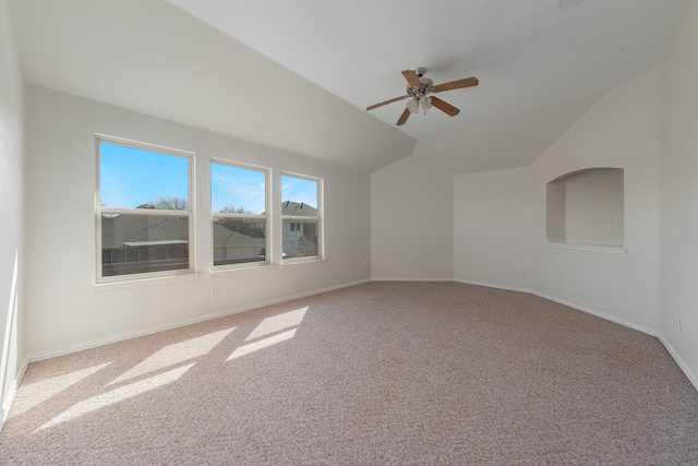 carpeted spare room featuring baseboards, vaulted ceiling, and a ceiling fan