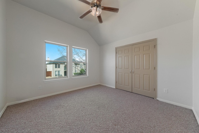 unfurnished bedroom featuring baseboards, lofted ceiling, ceiling fan, carpet, and a closet