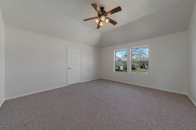 empty room featuring vaulted ceiling, carpet floors, ceiling fan, and baseboards