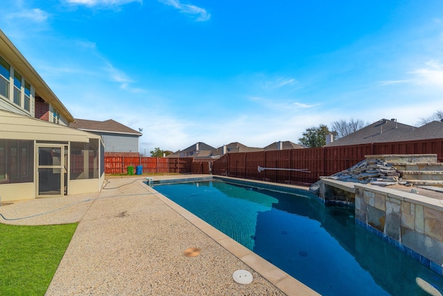 view of swimming pool featuring a fenced in pool, a patio area, a fenced backyard, and a sunroom