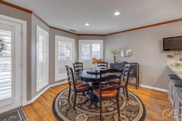 dining area with light wood-style floors, visible vents, crown molding, and baseboards