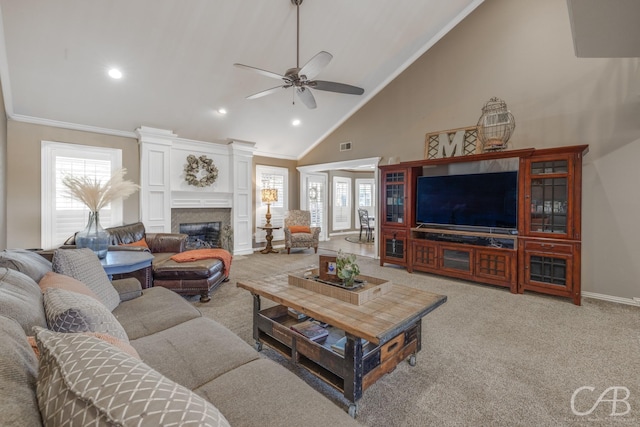 carpeted living area with baseboards, a ceiling fan, a glass covered fireplace, crown molding, and high vaulted ceiling