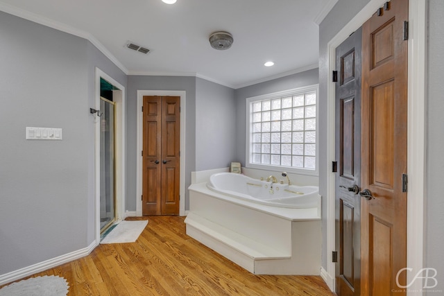 full bathroom featuring a garden tub, wood finished floors, visible vents, and crown molding