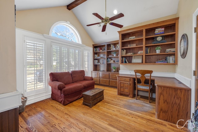 office area with vaulted ceiling with beams, ceiling fan, built in desk, and light wood-type flooring