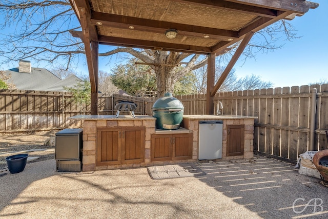 view of patio / terrace with a sink, exterior kitchen, a fenced backyard, and a grill