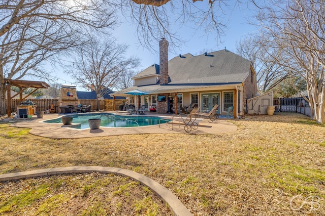 rear view of property featuring a storage shed, a patio, an outdoor structure, and a fenced backyard