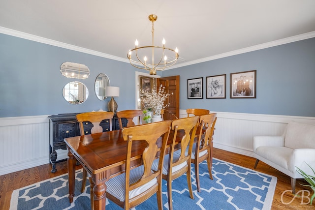 dining space featuring a chandelier, wainscoting, crown molding, and wood finished floors