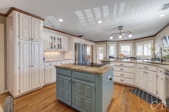 kitchen featuring visible vents, white cabinets, a kitchen island, appliances with stainless steel finishes, and a sink