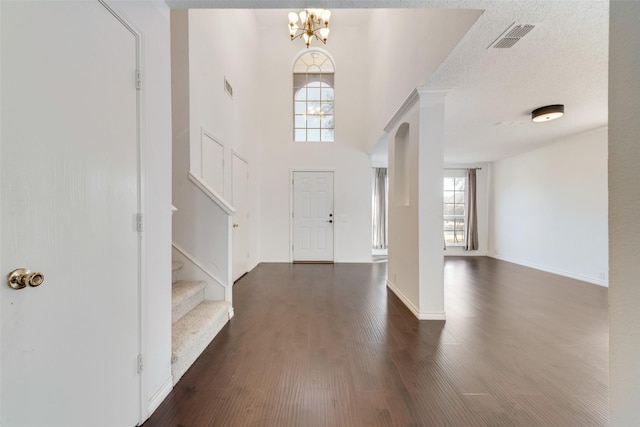 foyer with a textured ceiling, stairs, visible vents, and dark wood-type flooring