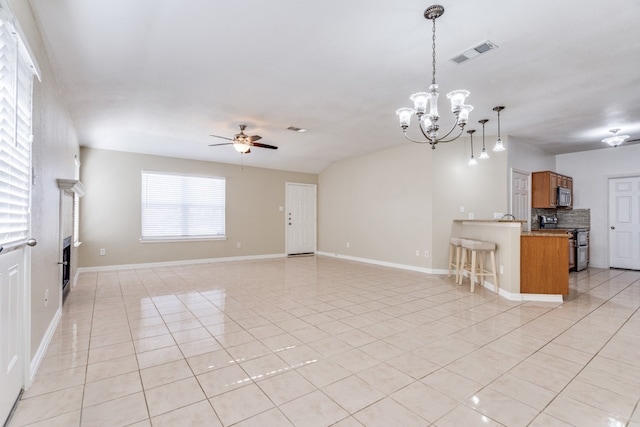 kitchen with light tile patterned floors, ceiling fan with notable chandelier, visible vents, appliances with stainless steel finishes, and brown cabinetry