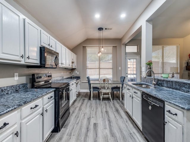 kitchen featuring lofted ceiling, a sink, visible vents, white cabinetry, and black appliances