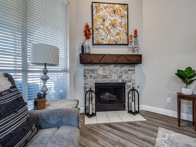 interior space featuring a stone fireplace, wood finished floors, and baseboards