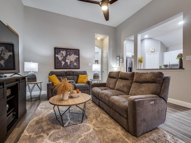 living room with a ceiling fan, baseboards, arched walkways, and wood finished floors