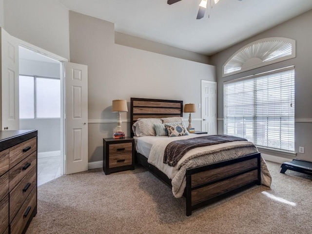 bedroom with ceiling fan, light tile patterned floors, baseboards, and light colored carpet