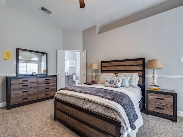 bedroom featuring a ceiling fan, light colored carpet, visible vents, and ensuite bath