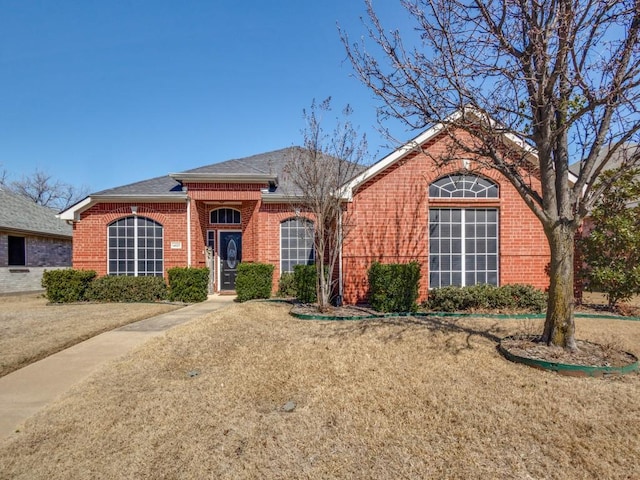 single story home featuring a shingled roof and brick siding