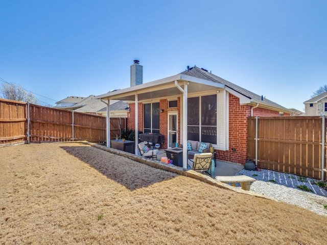 rear view of house featuring a patio area, a fenced backyard, a chimney, and brick siding